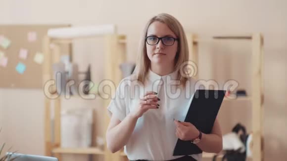 年轻女经理拿着剪贴板并邀请她在办公室工作视频的预览图