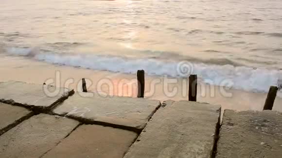 日落时海浪背景下的旧混凝土堤防用木栅粘贴毁坏视频的预览图