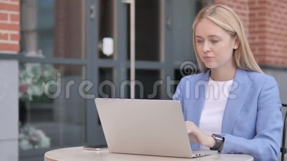 年轻女商人坐在户外的笔记本电脑在线视频聊天视频的预览图