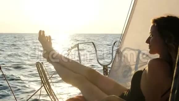 日落时分穿着泳装在帆船上打日光浴的女人视频的预览图