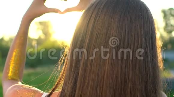 日落的心手女人用双手在日出或日落时塑造心灵在大自然的夏天女孩的心视频的预览图