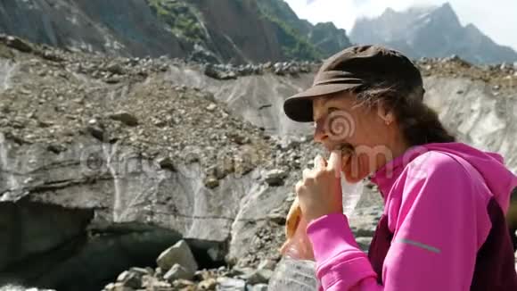 女游客在附近的山上喝水和吃面包视频的预览图