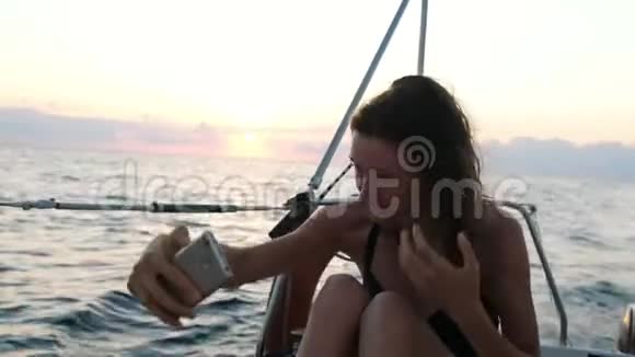 年轻女子驾驶游艇使用智能手机自拍视频的预览图