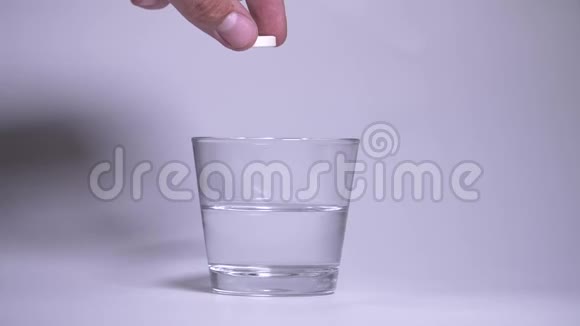 男人的手把橙色的泡腾片扔进一杯水里水中的气泡水沸腾和喷射都会使药丸溶解视频的预览图