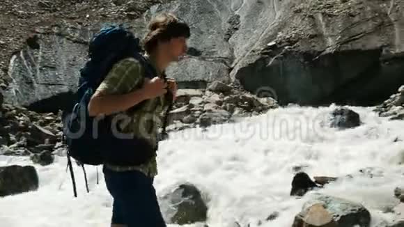 游客背着背包站在石头上在山上举起手臂视频的预览图