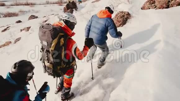 探险队里的游客一个接一个地带着大背包带着设备用滑雪杆帮助自己视频的预览图