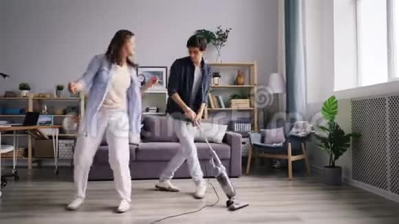男人打扫地板吸尘器和女朋友跳舞玩得开心视频的预览图