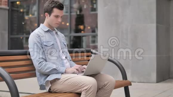 坐在室外头痛的年轻人手提电脑视频的预览图