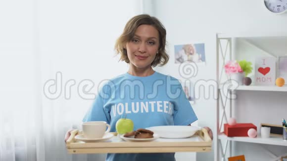 年轻的微笑志愿者手里拿着托盘手里拿着早餐食品视频的预览图