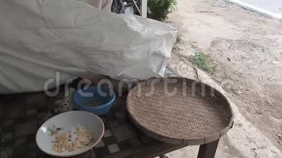一位老年妇女将阿拉伯咖啡豆从袋子里倒入圆形柳条脱粒篮或竹筛中视频的预览图