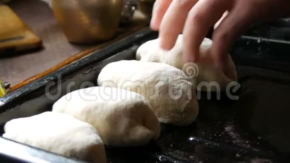 女人的手面包师把自制的烘焙面团以细长的圆球的形式连续放置在黑色烘焙片上视频的预览图