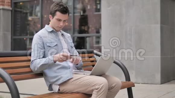 坐在长凳上的年轻人网上购物失败视频的预览图