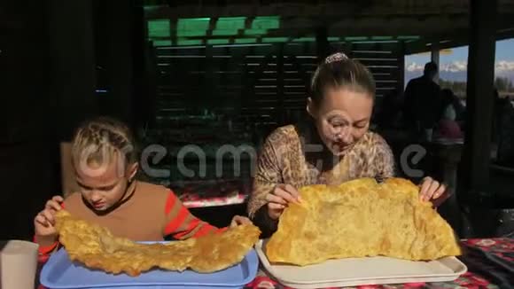 妇女和儿童吃国家布里亚特蒙古菜切布雷克大的大的68厘米的奶酪炸肉视频的预览图