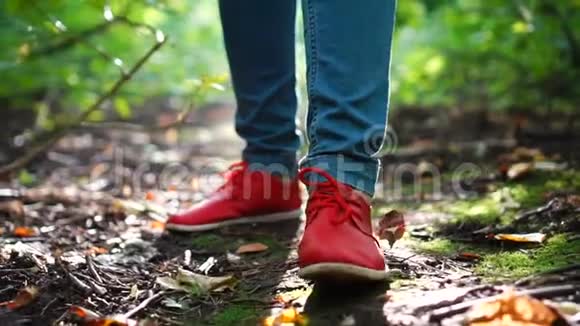 穿着红色鞋子的女性双脚穿过秋天的森林闭上眼睛视频的预览图