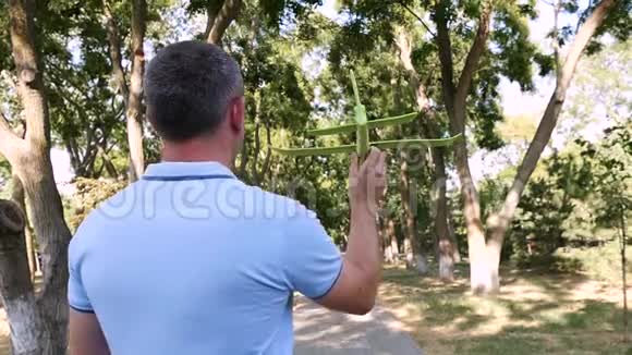 一个男人玩飞机在公园里阳光明媚的夏天把它扔到顺风飞机在缓慢地飞行视频的预览图