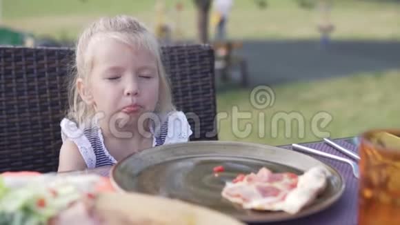 可爱的小女孩在街上的咖啡馆里吃披萨视频的预览图