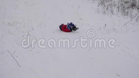 穿着红色夹克衫的快乐女孩在雪地里滑下山快乐的孩子在圣诞公园玩冬天慢慢视频的预览图