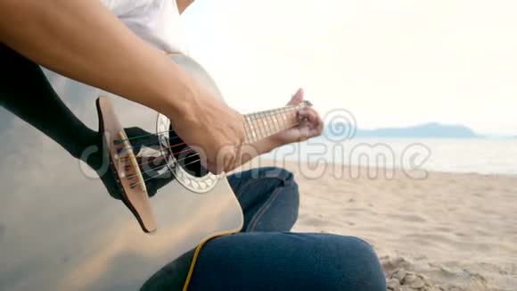 4K接近一个男人在日落时在海滩上弹声吉他感觉放松视频的预览图