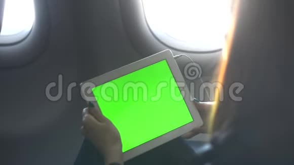 女人坐在经济舱通过耳机和平板电脑听音乐而喷气式飞机正在上升高度视频的预览图