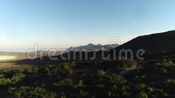 蓝色背景下绿色草地和灌木近高绿色山丘和山脉的鸟瞰图视频的预览图