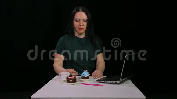 一个黑发女人在咖啡馆的餐桌上喝咖啡吃甜点蛋糕视频的预览图