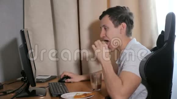 男人在家吃一片披萨在电脑上玩视频的预览图