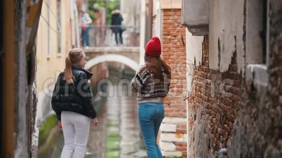 两个年轻的女游客站在街上望着水渠视频的预览图