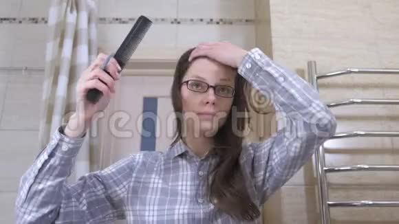 瞌睡的女人戴着眼镜在浴室梳着马尾辫视频的预览图