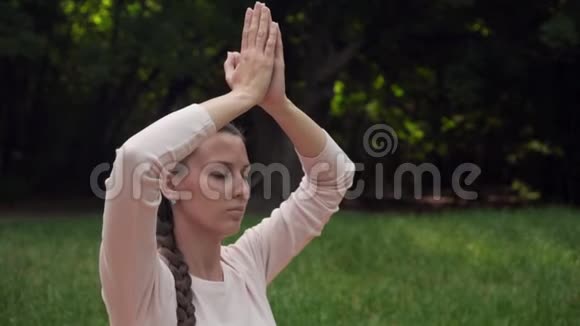 一位孕妇在公园里练习瑜伽坐在莲花的位置抱着她的手臂在上面冥想视频的预览图