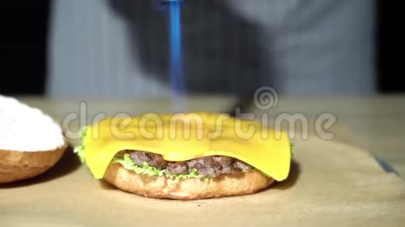 厨师用燃气燃烧器融化奶酪做汉堡包视频的预览图