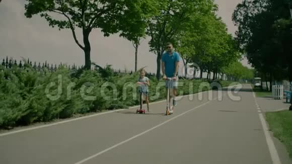 充满欢乐的父亲和女儿在公园里骑摩托车视频的预览图
