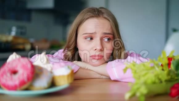 年轻女子在蔬菜和糖果之间选择伤心的女孩视频的预览图