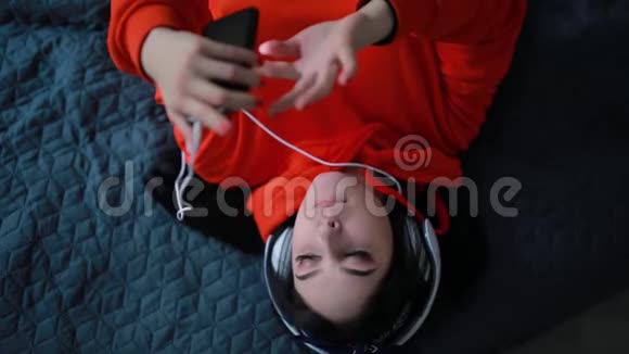 女孩躺在床上听耳机音乐俯视图视频的预览图