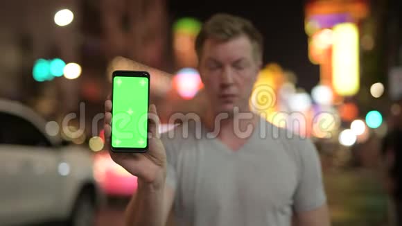 年轻快乐的游客晚上对着唐人街的街景播放电话视频的预览图