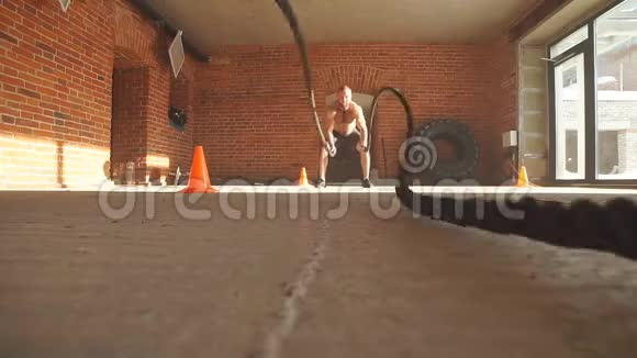 年轻的白种人在健身房用战绳锻炼慢动作视频的预览图