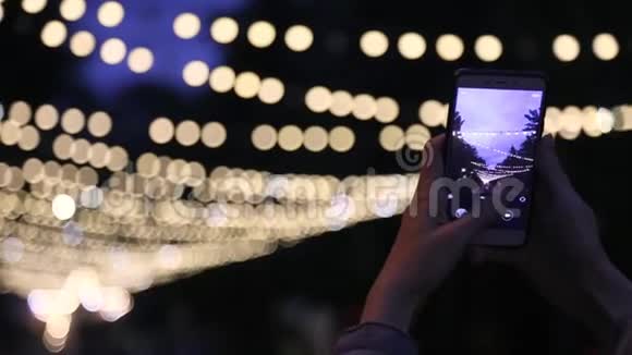 女孩在智能手机上拍摄夜灯杰兰圣诞节和背景视频的预览图