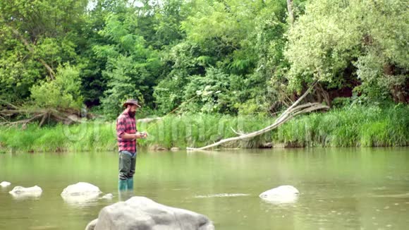 捕鱼英俊的渔夫拿着鱼竿在河里钓鱼渔夫钓到一条鱼鱼类和渔业视频的预览图