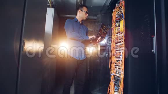 一名男性技师站在服务器机房操作他的笔记本电脑视频的预览图