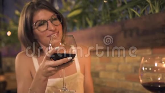微笑的女人手里拿着红酒杯在晚上的晚餐上说话快乐的女人喝红酒浪漫视频的预览图