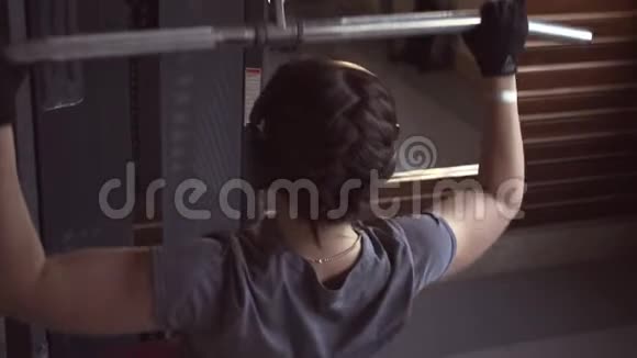 带耳机的女孩做背部肌肉锻炼视频的预览图