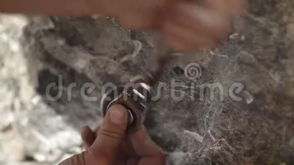 那个人的特写他的手把钥匙栓拧到岩石里为救援工作组织保险视频的预览图