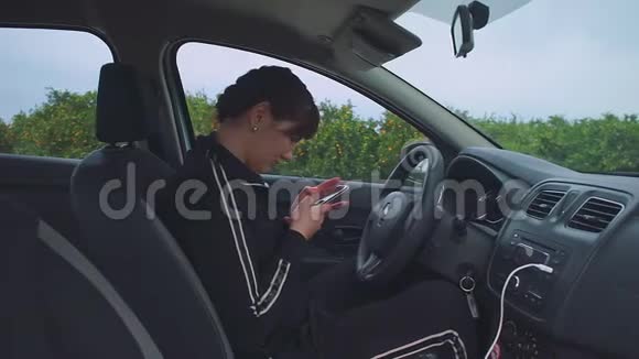布鲁内特坐在车里在智能手机上写信息视频的预览图
