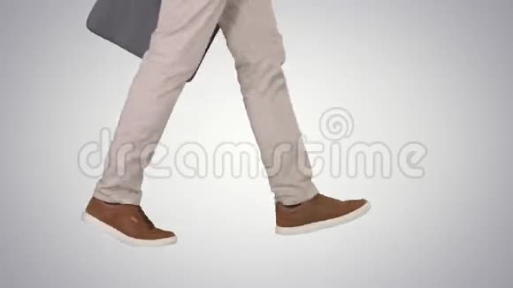 男人的脚是穿着牛仔裤和运动鞋在梯度背景下行走视频的预览图