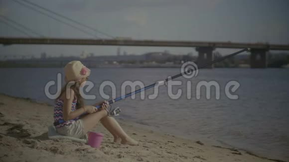 微笑的女孩坐在银行钓鱼的肖像视频的预览图