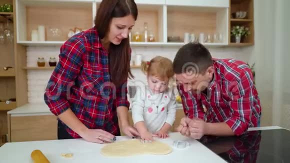 父母帮助他们的小女儿切饼干视频的预览图