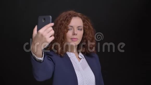 一位白种人成年美女的特写肖像她的红色卷发在电话前自拍视频的预览图