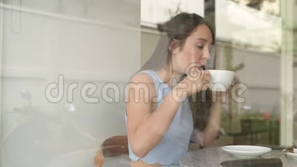 体贴的女商人一边喝咖啡一边用电话透过窗户看视频的预览图