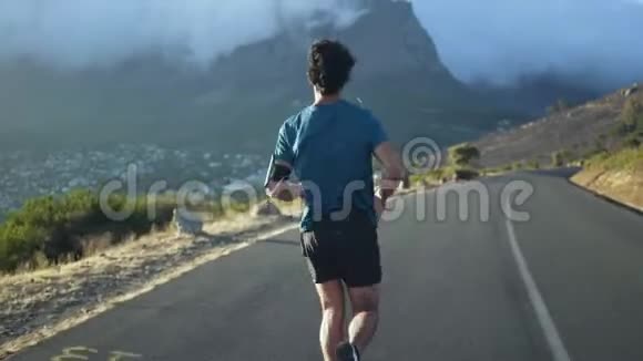 在山路上奔跑的男运动员的后景视频的预览图