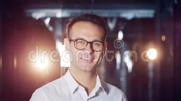 一个戴着眼镜的聪明人在一个有着闪光和玻璃般墙壁的房间里微笑视频的预览图