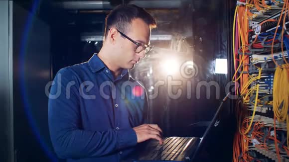 一位男工程师正在关闭他的笔记本电脑并微笑着走进摄像机的服务器机房视频的预览图
